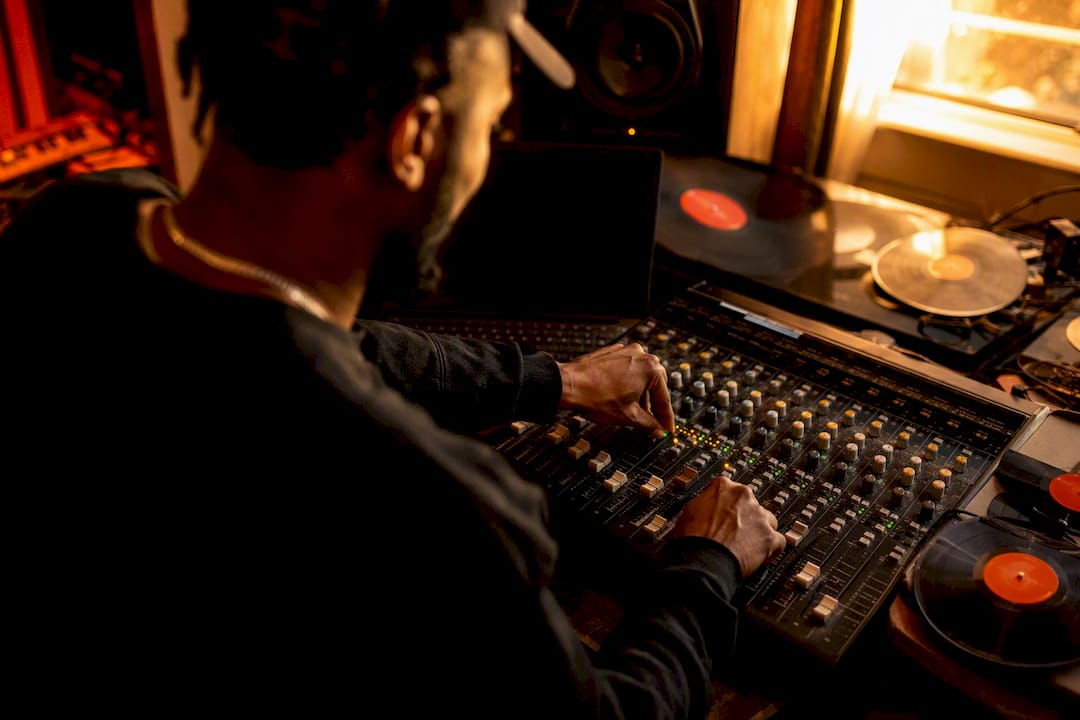 Hip hop artist adjusting studio mixer controls